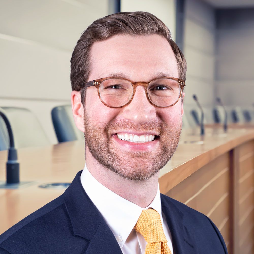 Andrew smiling standing in front of school board dais