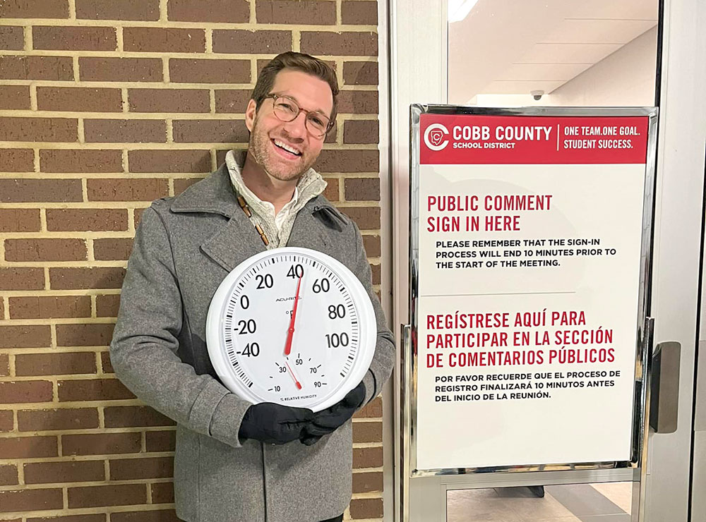 Andrew standing outside at the CCSD public comment line holding a thermometer