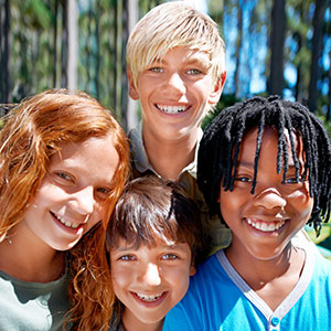 A diverse group of kids smiling with a wooded forest in the background